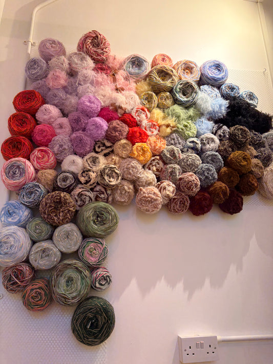 Colorful yarn balls arranged in a pattern on a white surface.
